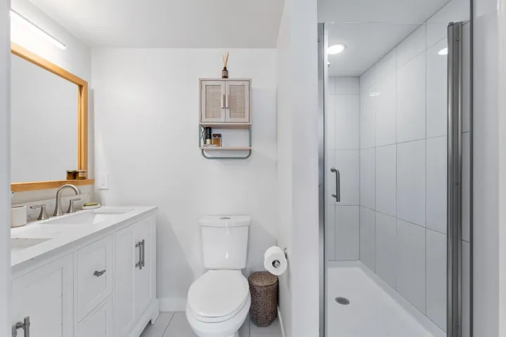 Bathroom with double vanity, a stall shower, and light tile patterned flooring