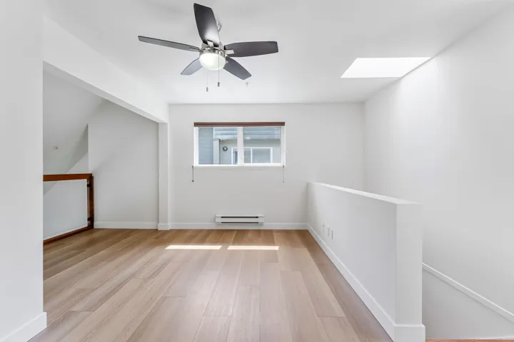 Additional living space with a skylight, light wood finished floors, ceiling fan, and a baseboard radiator