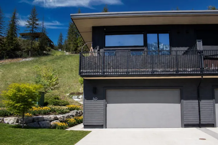 Contemporary multi-level exterior with dark gray siding and a light gray garage door