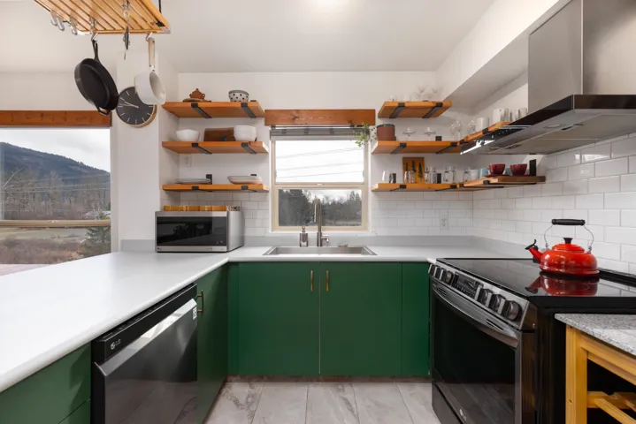 Kitchen with a sink, stainless steel microwave, electric range oven, wall chimney exhaust hood, and dishwashing machine
