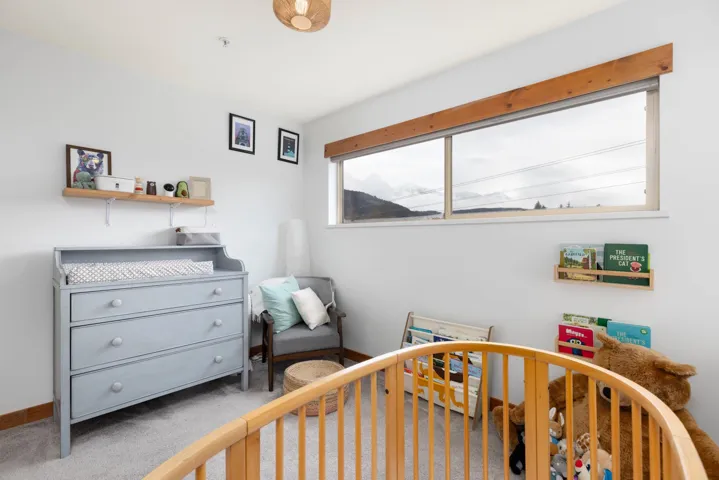 Carpeted bedroom featuring baseboards and a crib