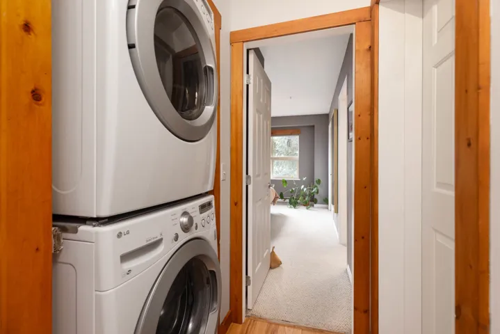 Laundry room featuring light carpet, laundry area, and stacked washing maching and dryer