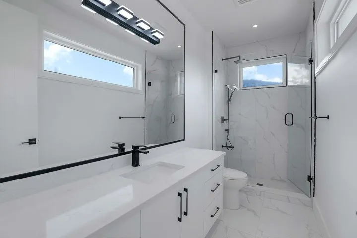 Full bath featuring healthy amount of natural light, marble finish floors, vanity, and a marble finish shower