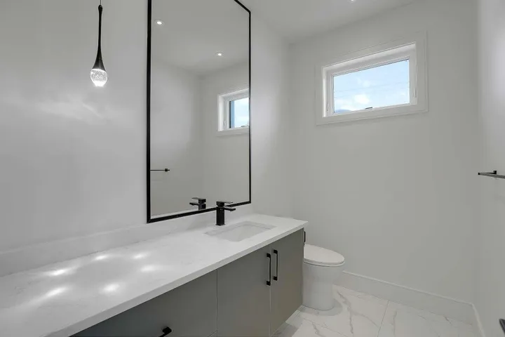 Bathroom featuring vanity, toilet, marble finish flooring, and baseboards