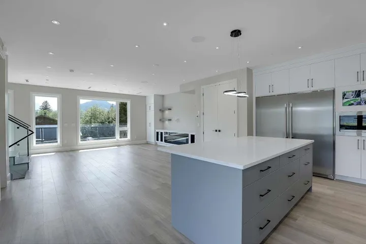 Kitchen featuring stainless steel built in refrigerator, open floor plan, a kitchen island, light wood-style flooring, and white cabinets