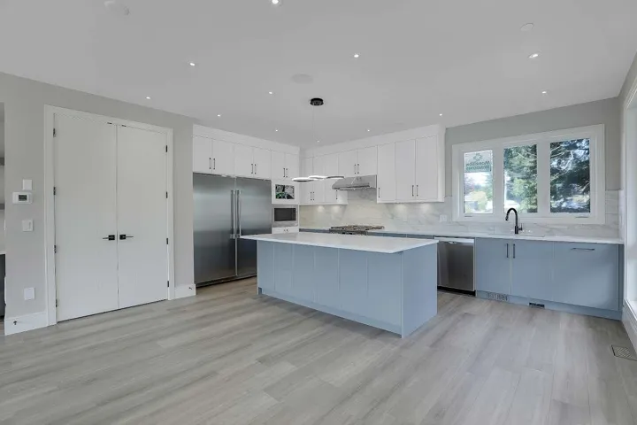 Kitchen featuring stainless steel appliances, under cabinet range hood, light countertops, a kitchen island, and tasteful backsplash