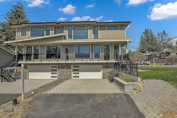 View of front of home with stairway, driveway, an attached garage, and covered porch