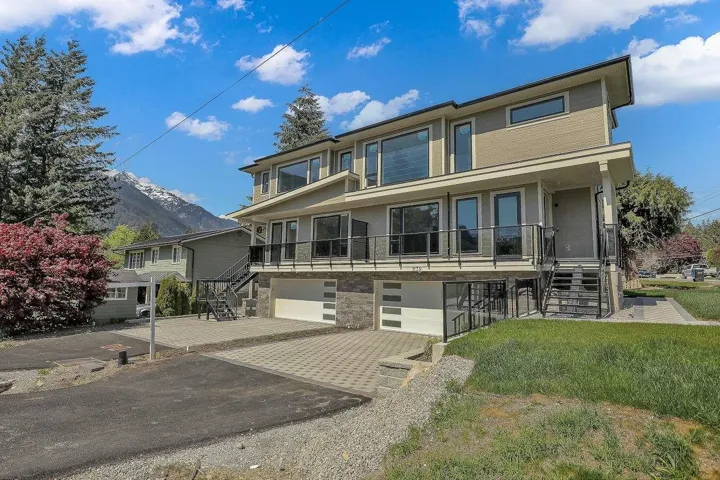 View of front of house with stairs, a garage, driveway, and stone siding