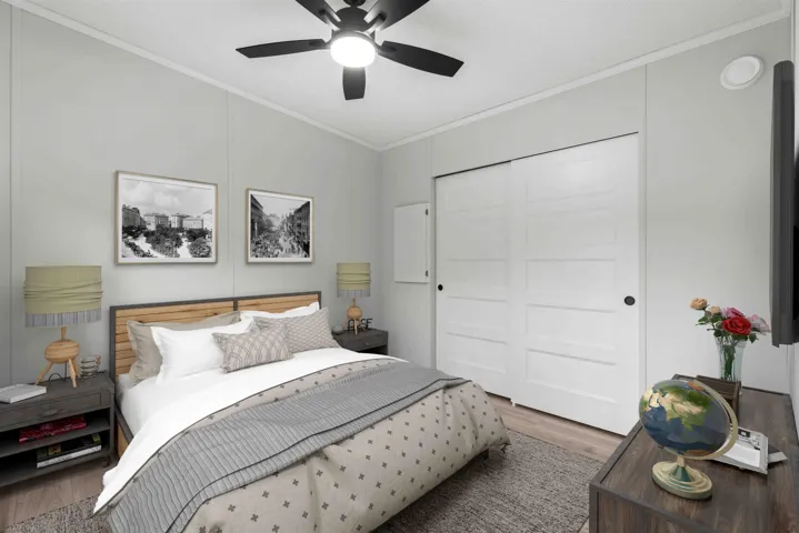 Bedroom featuring crown molding, wood finished floors, a ceiling fan, and a closet. Photo has been virtually staged.