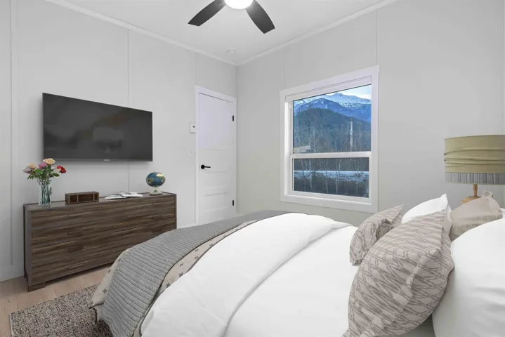 Spacious bedroom with mountain views, crown molding, and ceiling fan. Photo has been virtually staged.