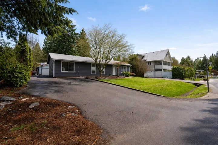 Ranch-style home featuring a front yard, a garage, an outdoor structure, and asphalt driveway