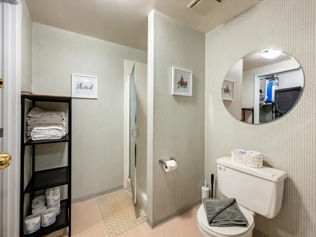 Full bath with wallpapered walls and a shower stall