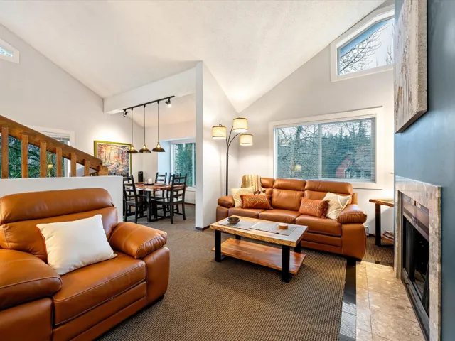 Living area featuring high vaulted ceiling, track lighting, a fireplace, and carpet flooring