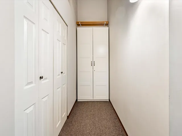 Hallway with dark colored carpet and baseboards