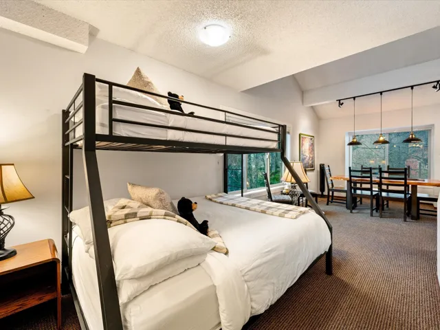 Bedroom featuring vaulted ceiling, dark colored carpet, track lighting, and a textured ceiling
