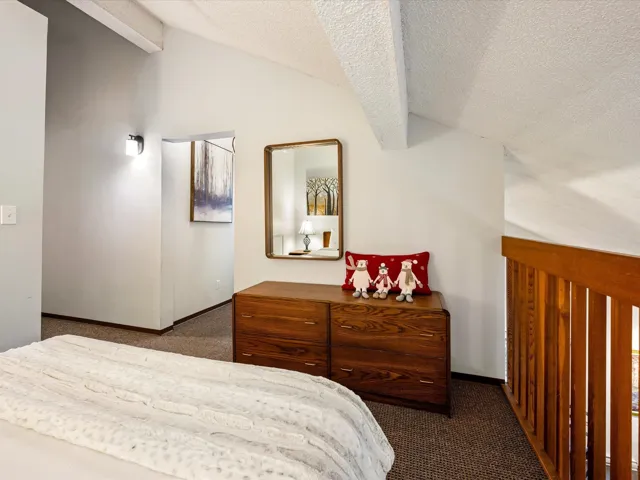 Bedroom with carpet flooring, vaulted ceiling, and a textured ceiling