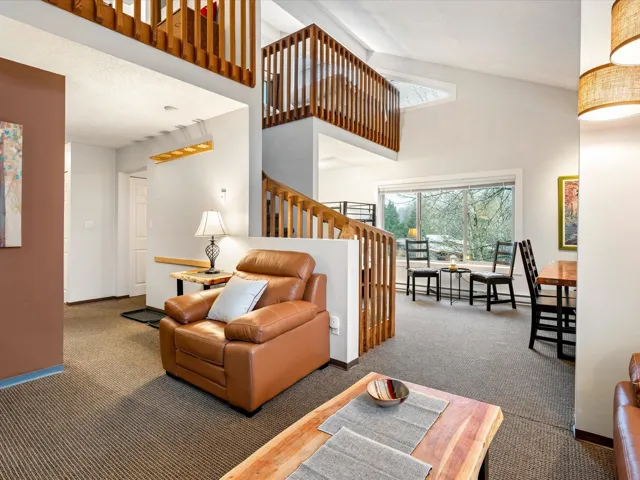 Living area featuring high vaulted ceiling, carpet flooring, and baseboard heating