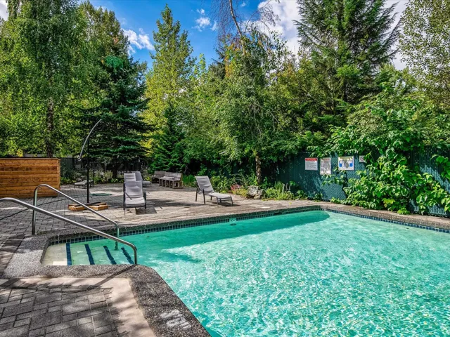 Community pool with a patio area and view of scattered trees