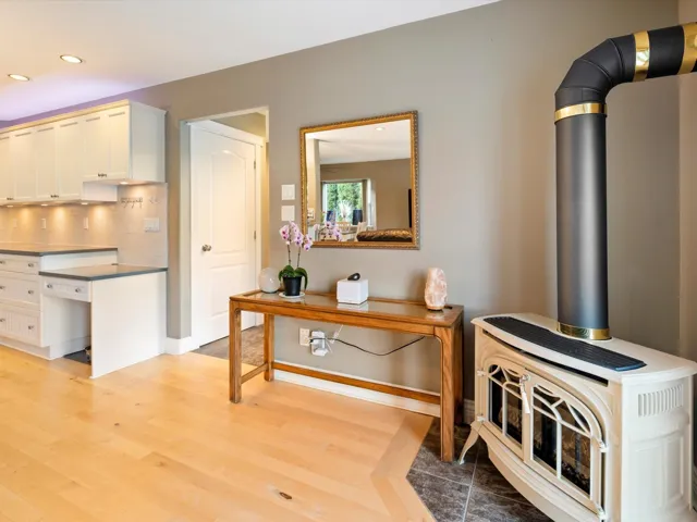 Interior space featuring recessed lighting, backsplash, light wood-style floors, a wood stove, and white cabinetry