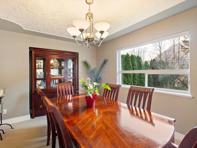 Dining space with light carpet, a notable chandelier, a textured ceiling, and baseboards