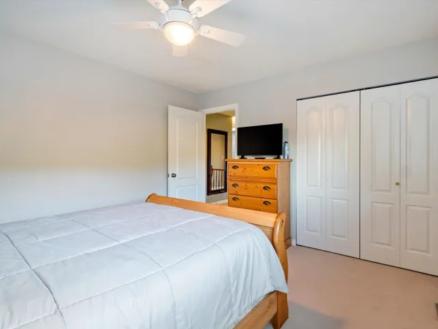 Bedroom with light carpet, ceiling fan, and a closet