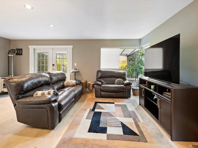 Living area with recessed lighting, a wood stove, light wood-style flooring, and french doors
