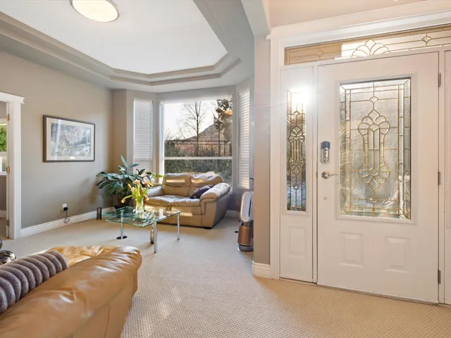 Entrance foyer with plenty of natural light, a tray ceiling, baseboards, and light colored carpet