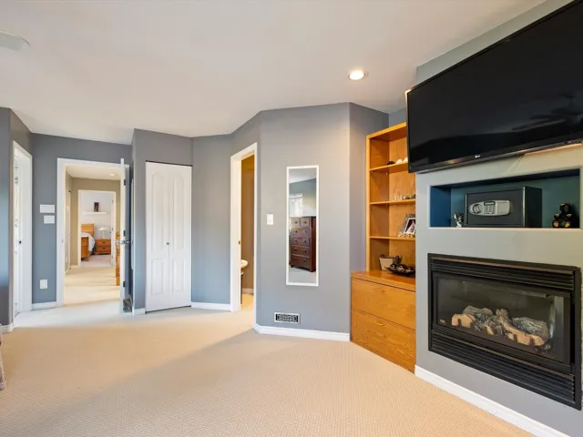 Living room with light carpet, baseboards, visible vents, and a glass covered fireplace