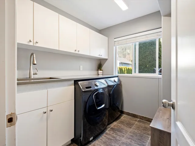 Laundry room featuring separate washer and dryer, a sink, cabinet space, and baseboards
