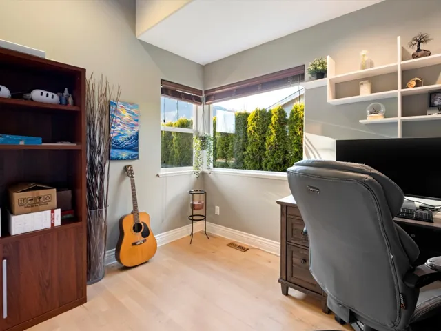 Office area with light wood finished floors, visible vents, and baseboards