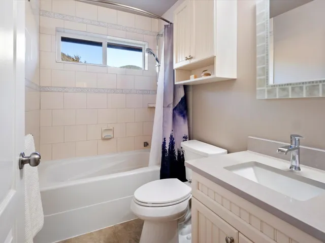 Bathroom with tile patterned flooring, shower / tub combo with curtain, vanity, and toilet