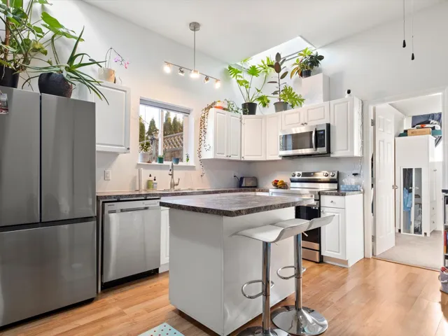 Kitchen with appliances with stainless steel finishes, dark countertops, and white cabinetry