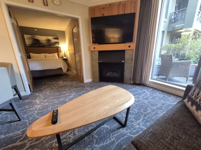 Bedroom featuring access to exterior, a large fireplace, dark carpet, and ornamental molding