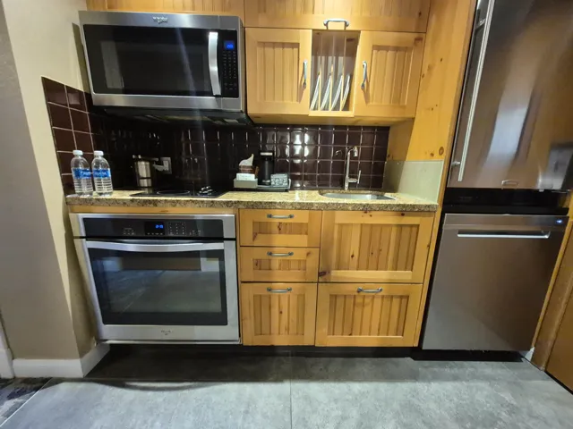 Kitchen featuring appliances with stainless steel finishes, backsplash, and light stone counters