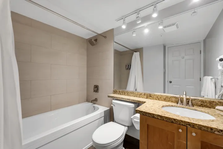 Bathroom with vanity, shower / tub combo, and rail lighting