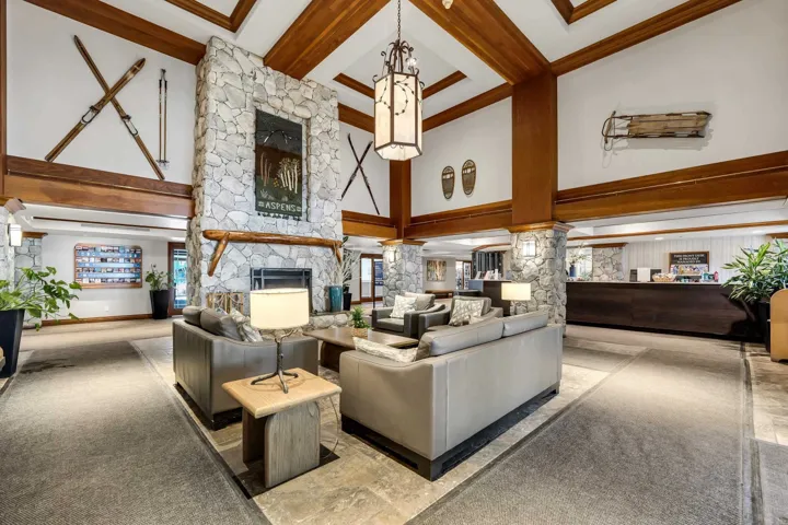 Carpeted living room with ornate columns, a fireplace, and coffered ceiling