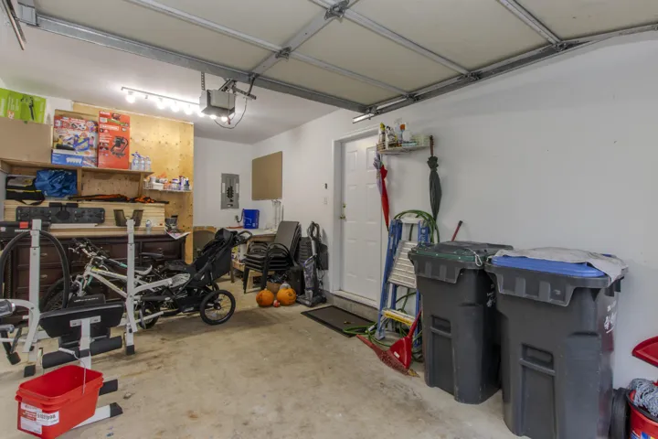 Garage with electric panel, a garage door opener, and a workshop area