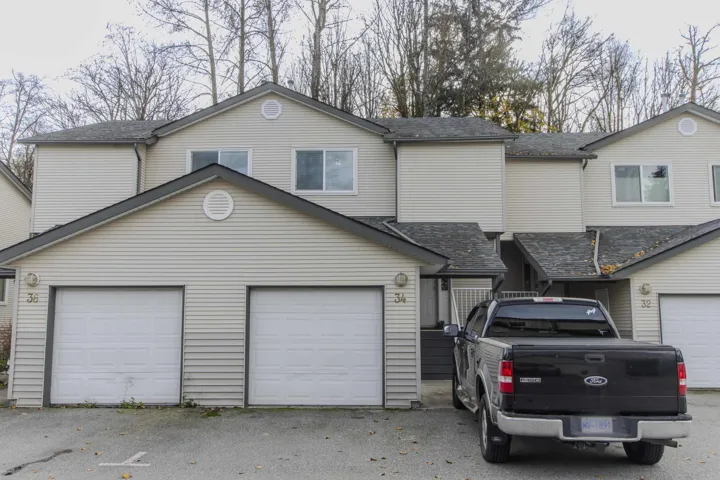 View of front facade with a shingled roof, a garage, and driveway