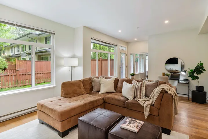 Living room with baseboard heating, light wood finished floors, and recessed lighting