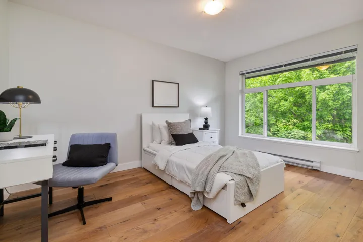 Bedroom with a baseboard heating unit, light wood-type flooring, and baseboards