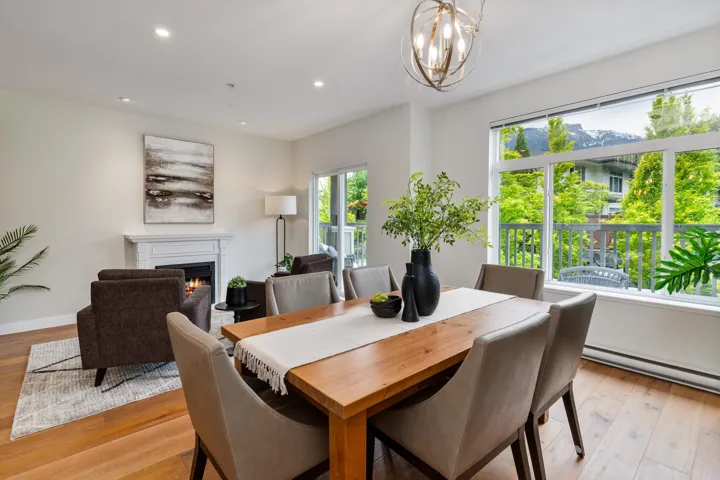 Dining space with a warm lit fireplace, a chandelier, light wood-style floors, recessed lighting, and baseboards