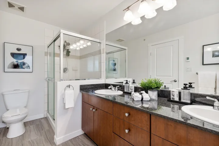 Bathroom with a shower stall, toilet, double vanity, and baseboards
