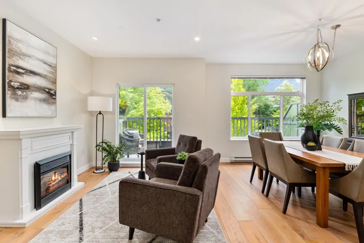 Living room featuring baseboard heating, light wood-style flooring, a glass covered fireplace, and recessed lighting