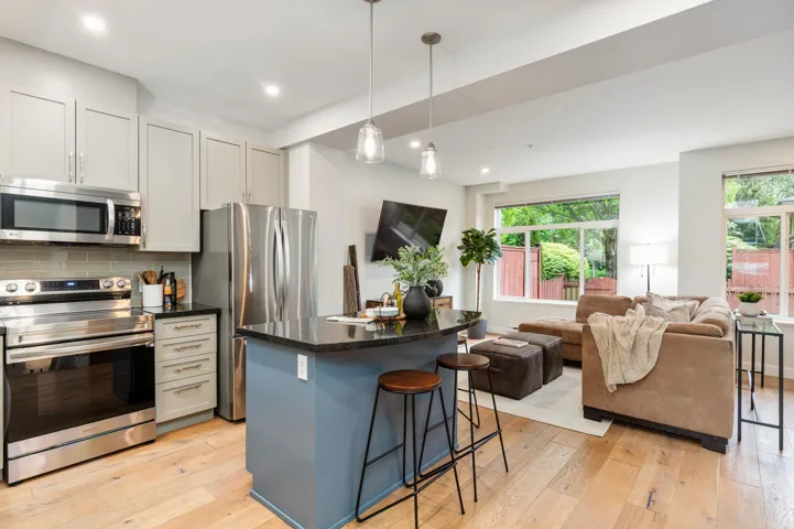 Kitchen featuring appliances with stainless steel finishes, light wood-style flooring, a kitchen bar, open floor plan, and a center island