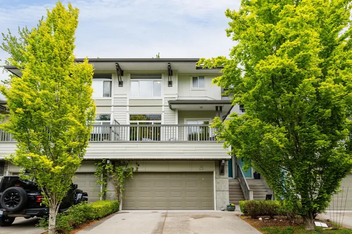 Multi unit property with concrete driveway, an attached garage, a balcony, and stairs