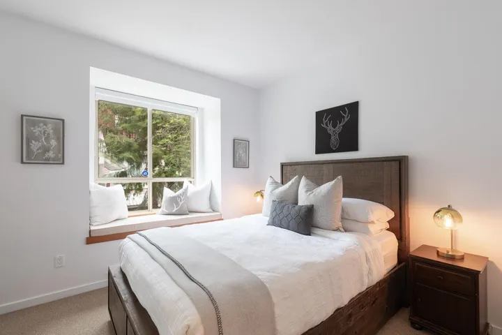 Bedroom featuring a large picture window with a built-in window seat, wood-finish flooring, and a textured headboard