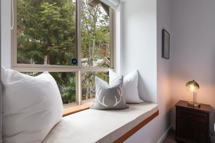 Built-in window bench with a light-colored cushion and wood-finish trim, situated beneath a large multi-pane window