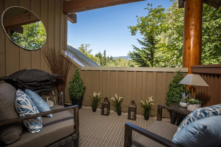 Private outdoor patio with a planked wood wall, exposed wood beam, and a partial outdoor ceiling