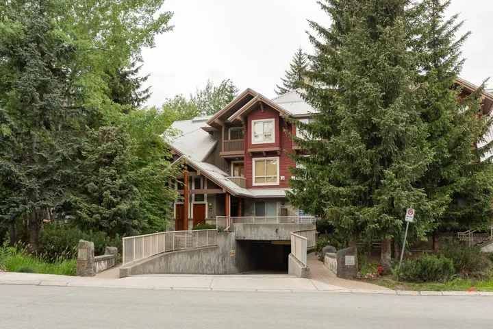Contemporary multi-story building featuring warm red siding accents and a pitched roofline