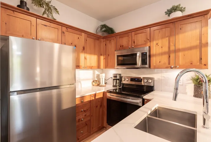Corner kitchen featuring wood cabinetry with crown molding